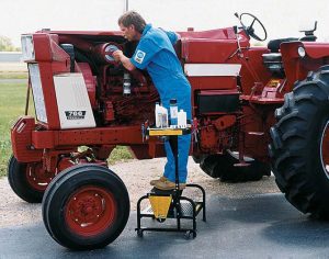 A guys is standing on a sturdy steps while working on a tractor.