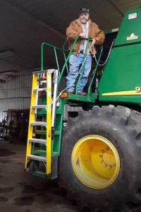 Retractable combine cab access ladder that a guys is pulling up.