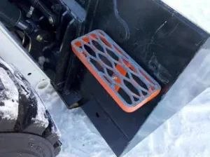 A step on a bucket that's attached to a skid steer.